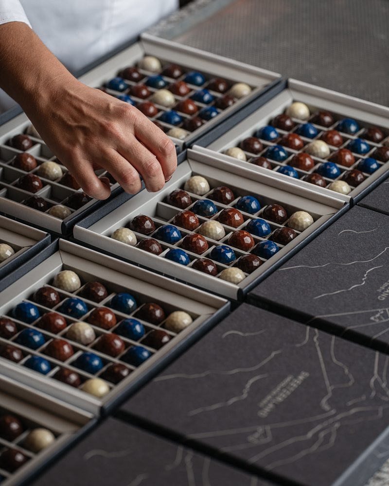 Boxes of faceted chocolates being filled by hand